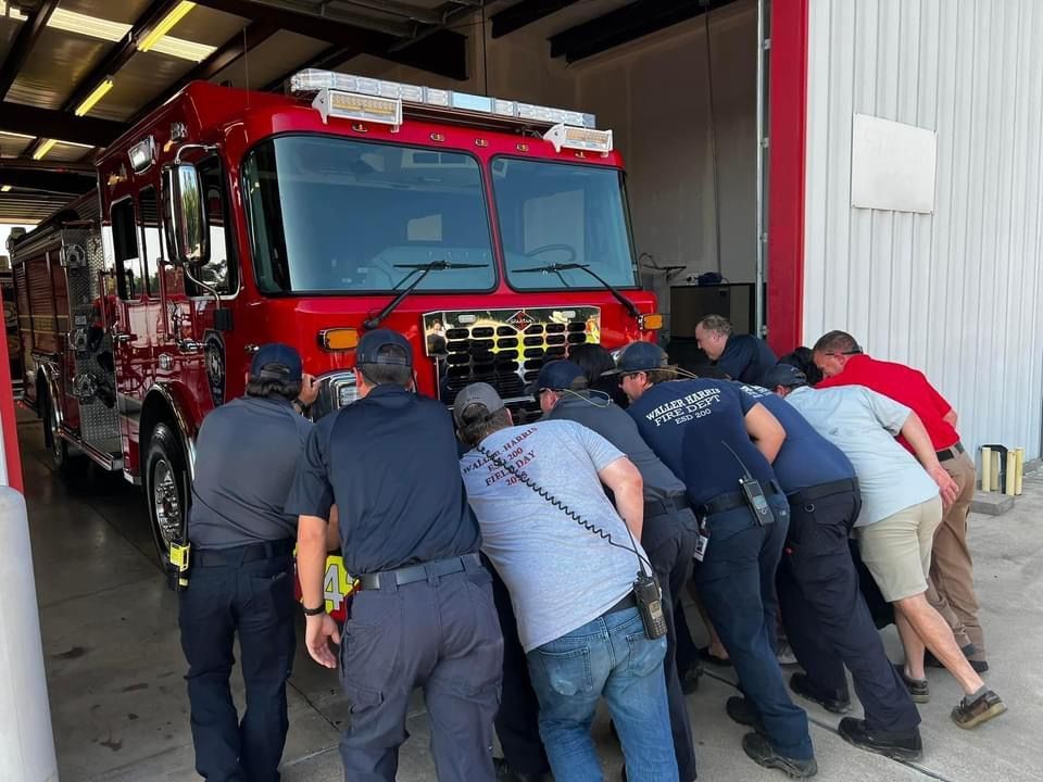 A group of fire fighters are pushing in a new fire engine into the fire station.