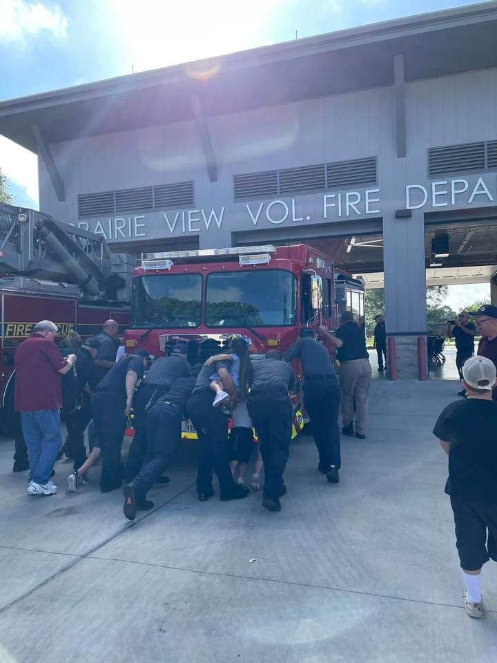 A group of fire fighters pushing a new fire engine into a fire station.