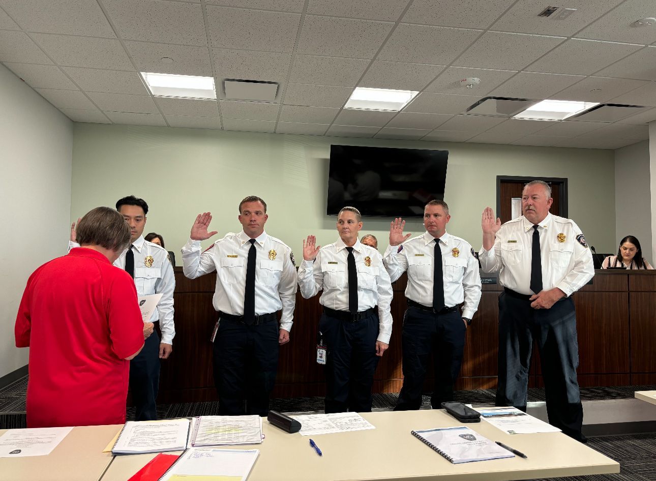 A group of police officers are taking oaths in a courtroom.