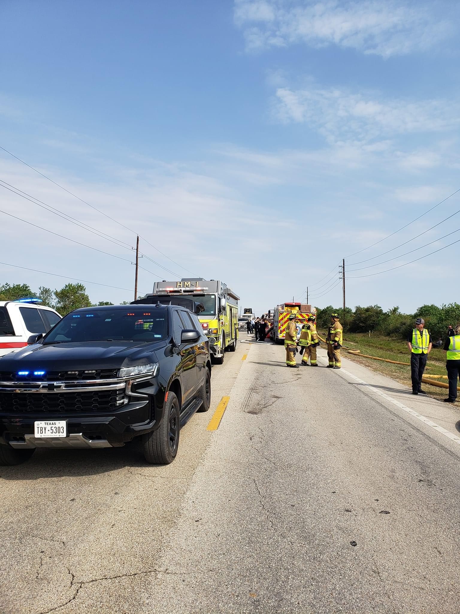 A group of firefighters are standing on the side of a road.