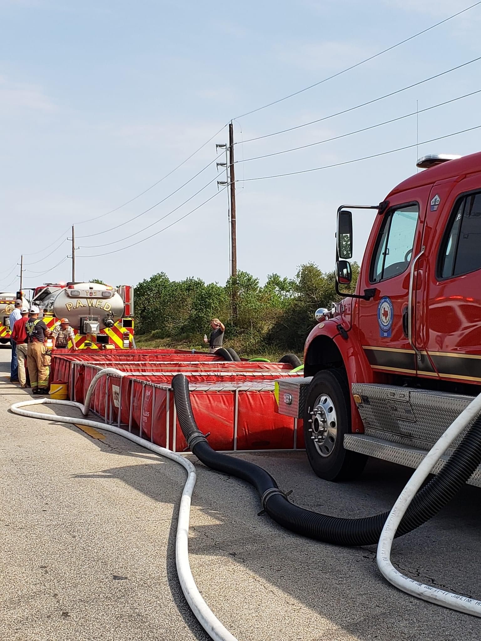 A fire tanker truck is parked next to tanks of water.