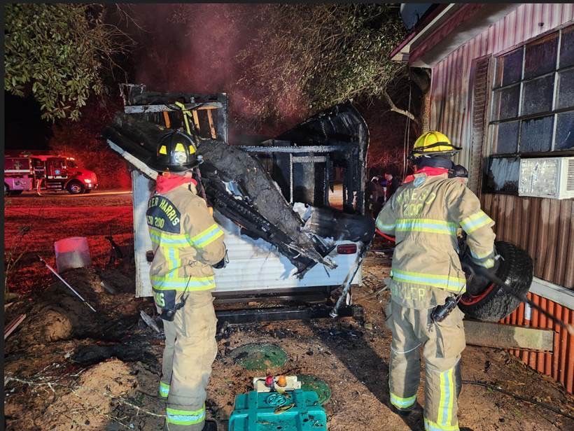 Two fire fighters overhaul a camper after a fire.