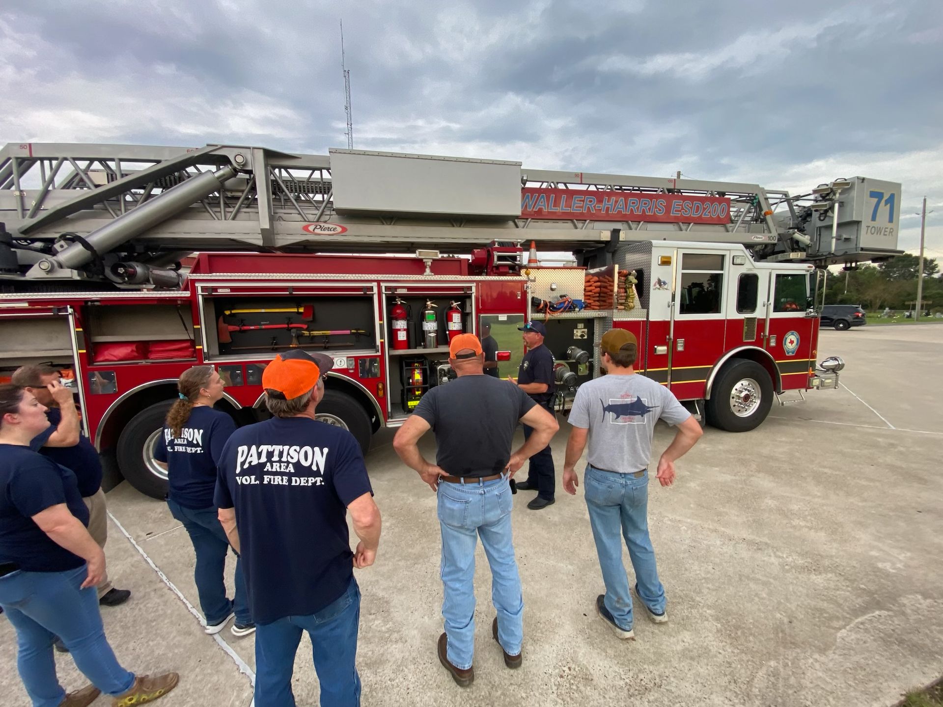 A group of people are standing in front of a aerial fire truck.