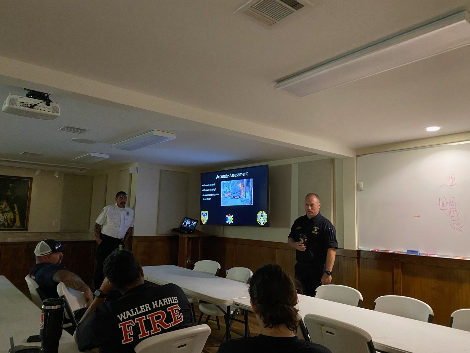 A man wearing a shirt that says fire is giving a presentation to a group of people.