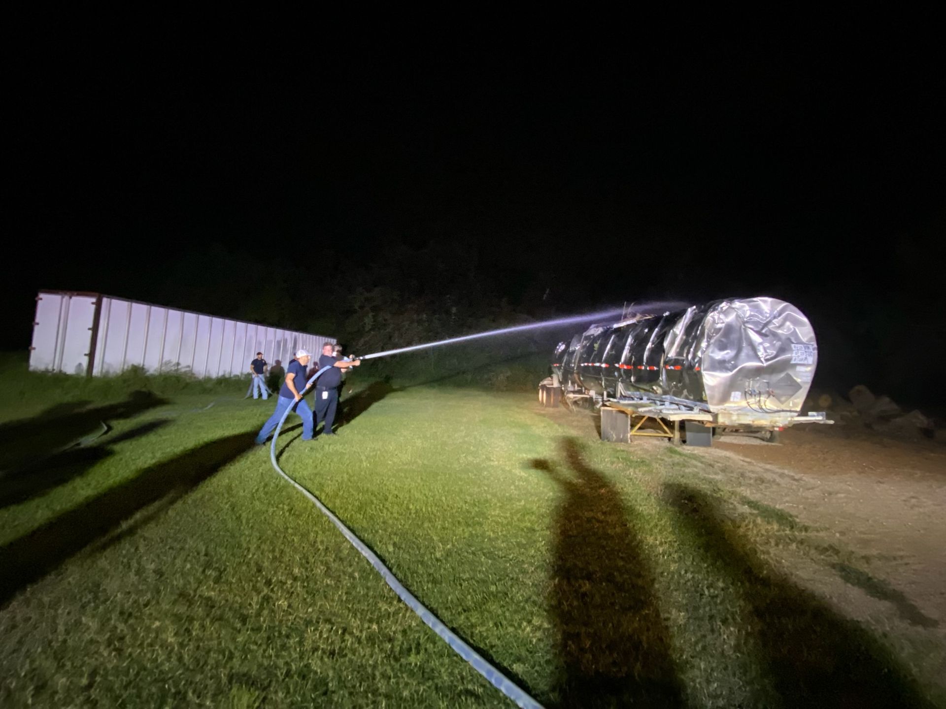 A group of Pattison volunteer fire fighters spraying a water on a training prop.