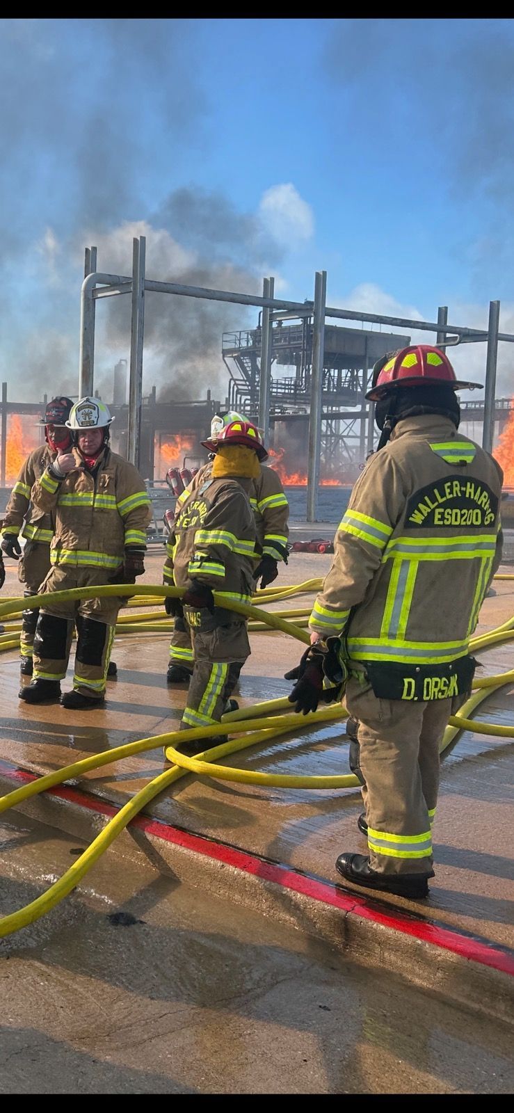 A group of firefighters are standing next to each other in front of a fire.