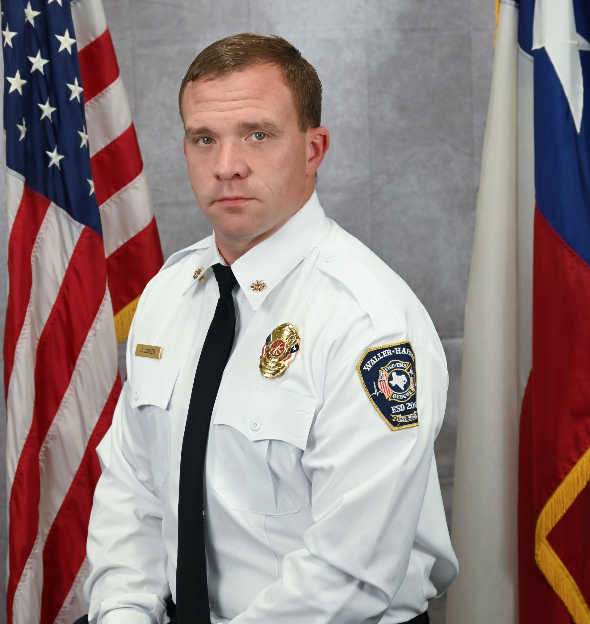 Portrait of Assistant Chief of Operations James Jones seated before U.S. and Texas flags, facing the camera.