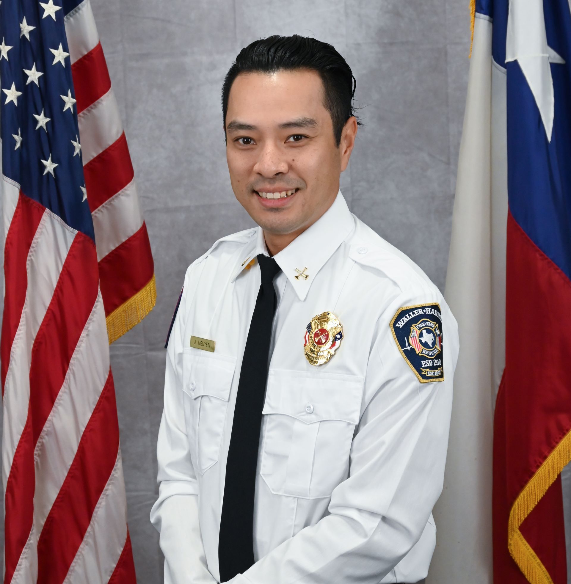 A picture of Commissioner Sherry Whiteley wearing a black shirt standing next to an American Flag.