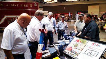A group of men are looking at a display at a fire show.