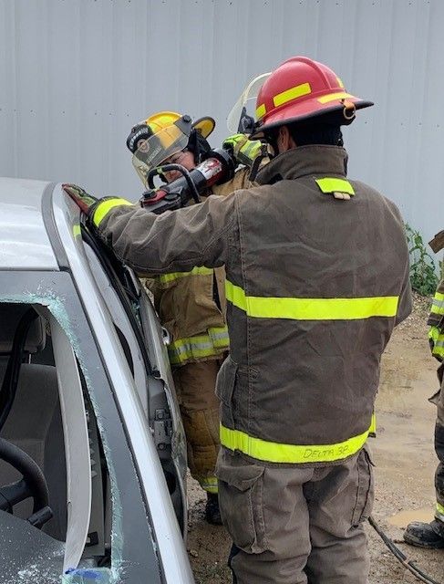 A group of firefighters are working on a car.