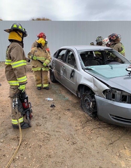 A group of firefighters are working on a vehicle that has turned over during a training exercise.