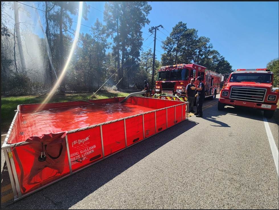 Two fire trucks are parked next to a large red pool