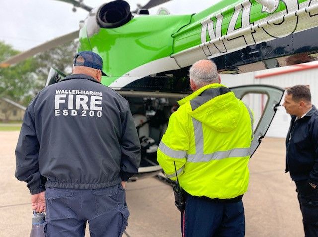 Three men are standing in front of a green and white Life Flight helicopter.