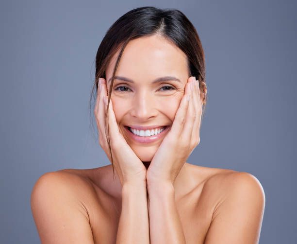 A Woman Is Smiling with Her Hands on Her Face — Palm Beach Currumbin Injectables in Currumbin, QLD