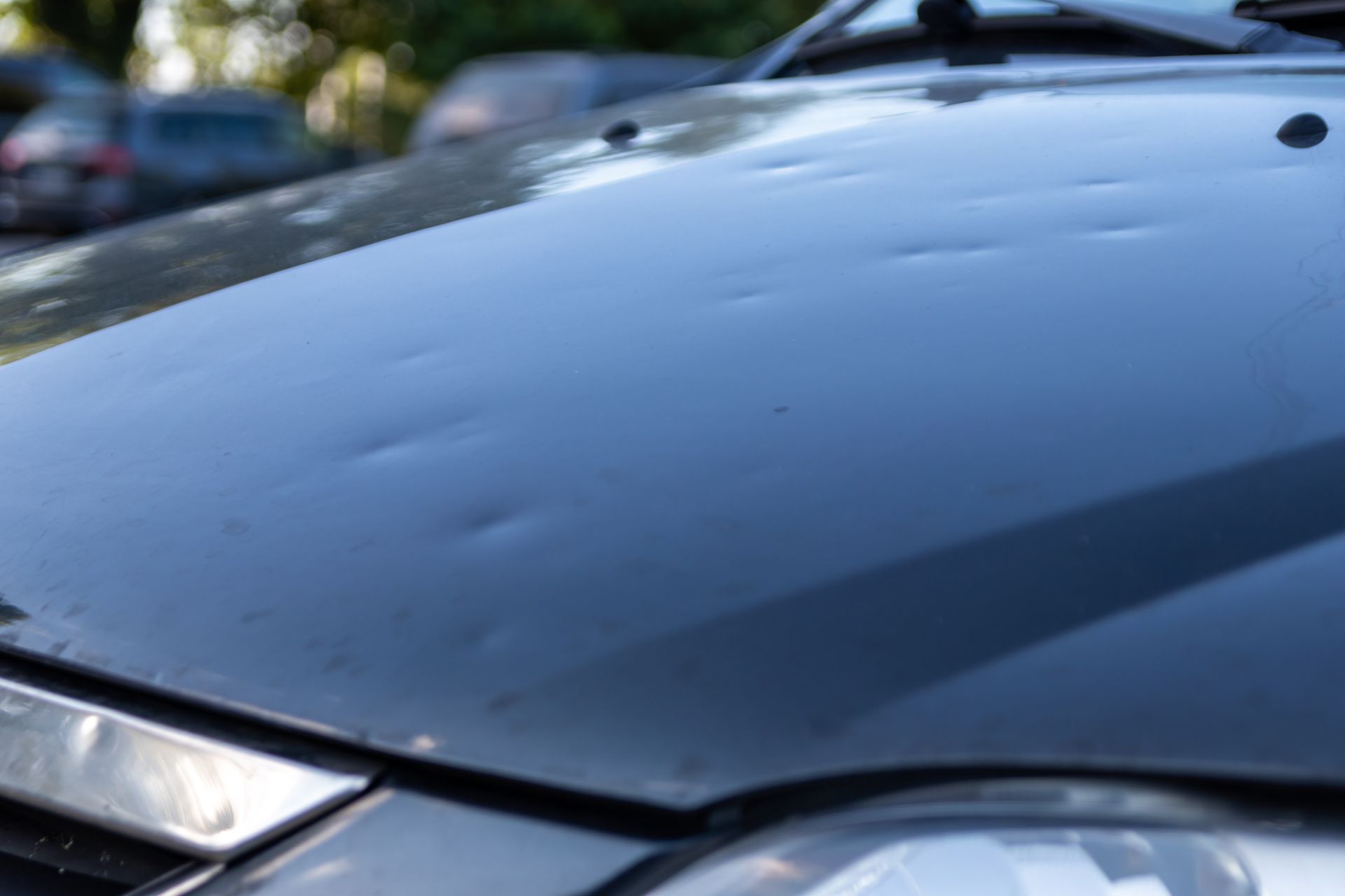 A close up of a car hood with hail damage.