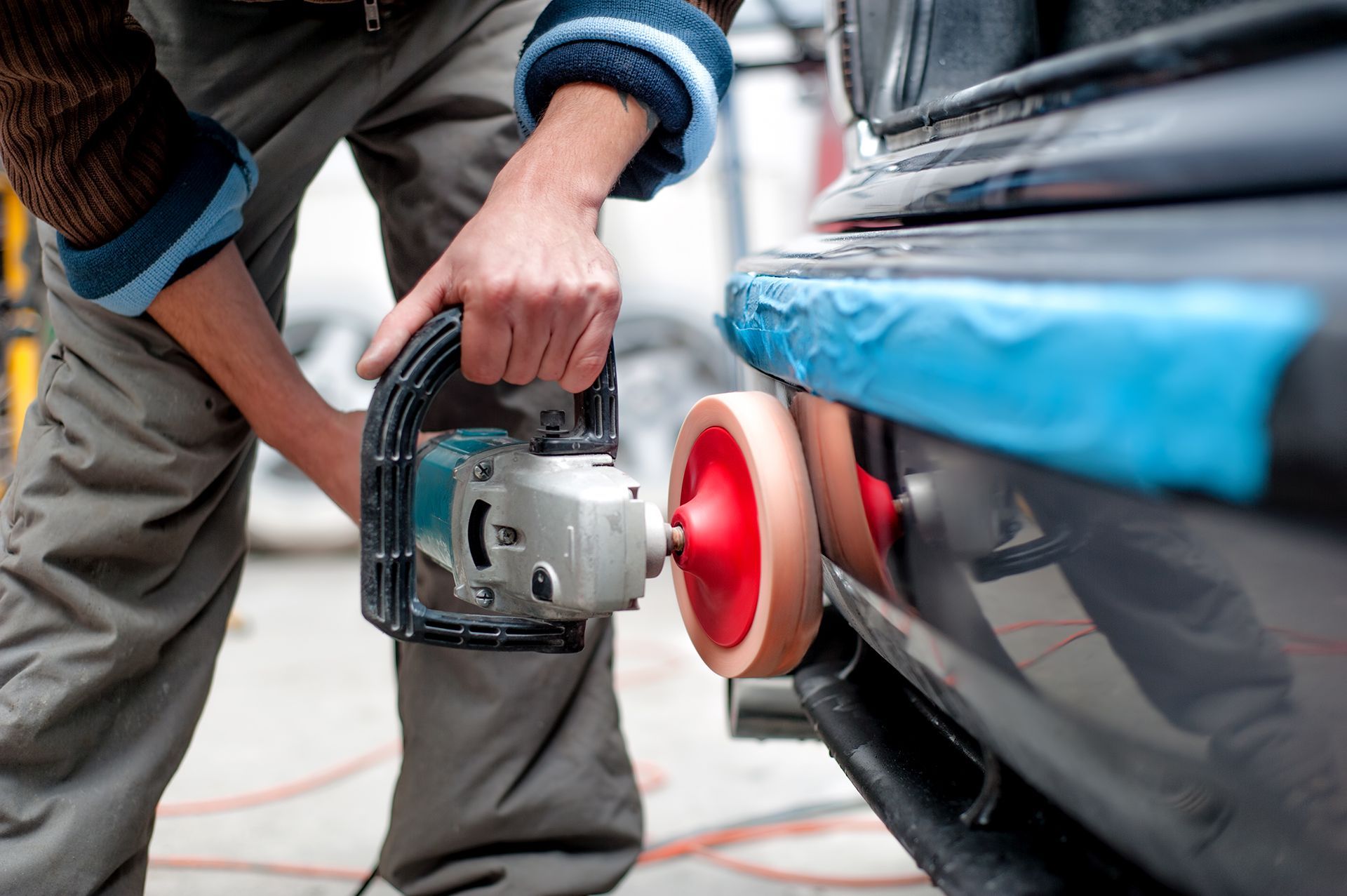 A man is polishing a car with a machine.