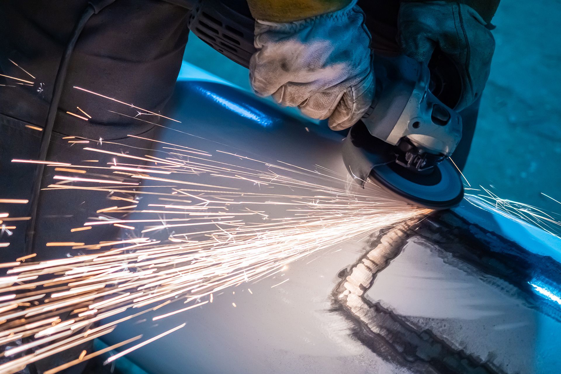 A person is grinding a piece of metal with sparks coming out of it.