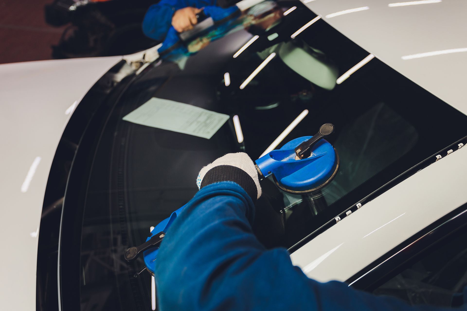 A person is fixing a windshield on a car.