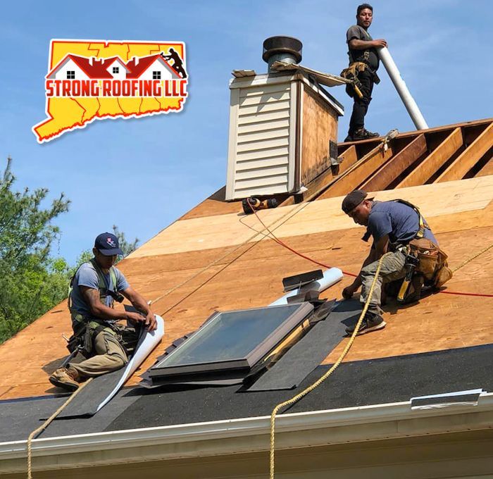 Roofers working on a house, installing shingles near a skylight. The logo for Strong Roofing LLC is in the upper left corner.