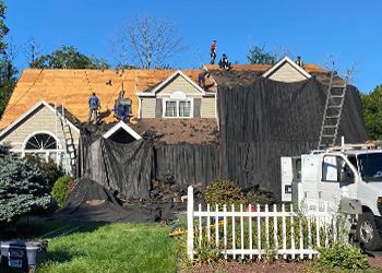 A group of people are working on the roof of a house.