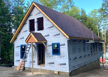 A house is being built with a ladder on the side of it.