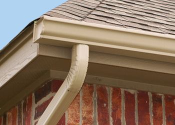 A close up of a gutter on the side of a brick house.