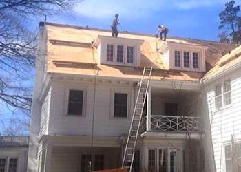 Two men are working on the roof of a house.