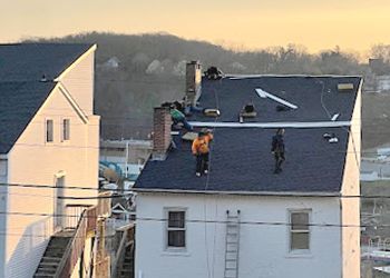 A group of people are working on the roof of a house.