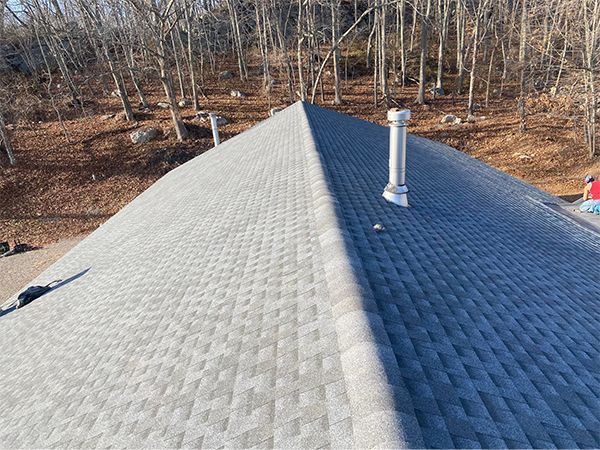 A roof with a chimney on top of it and trees in the background.