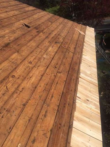 Wooden planks forming a roof surface, partially covered with new, lighter-colored boards along the edge.