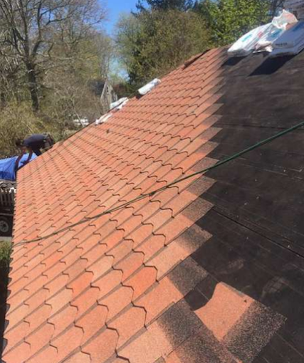 A roof partially covered with red shingles during a re-roofing project, with the other half showing black underlayment.