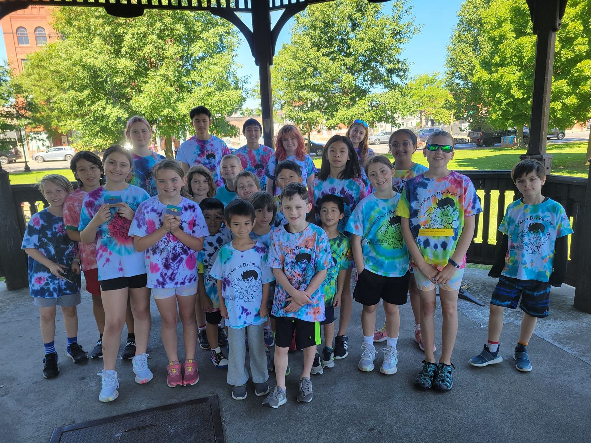 a group of children wearing karate uniforms and yellow belts are posing for a picture .