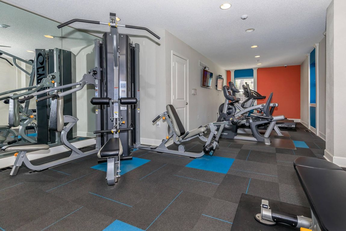 A gym with a lot of exercise equipment and a mirror.