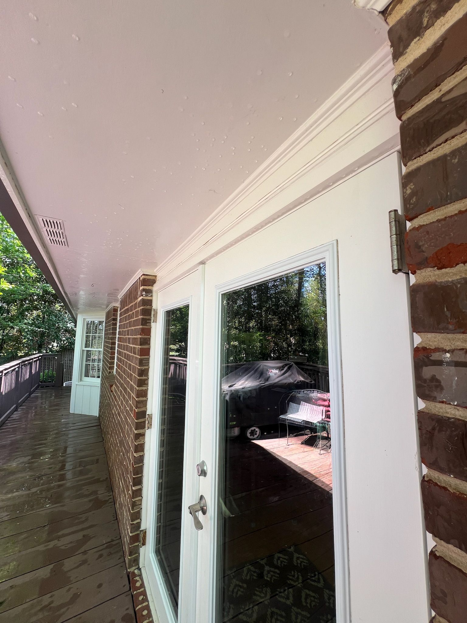 A white door with a mirror on it is on a brick building.