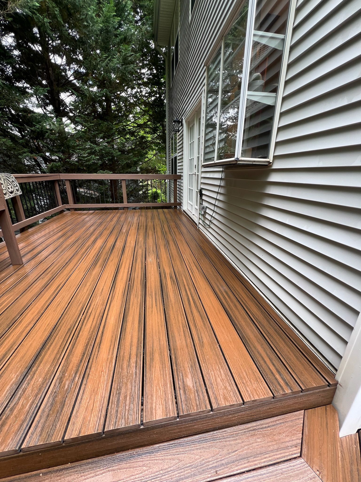 A wooden deck is sitting next to a white house.