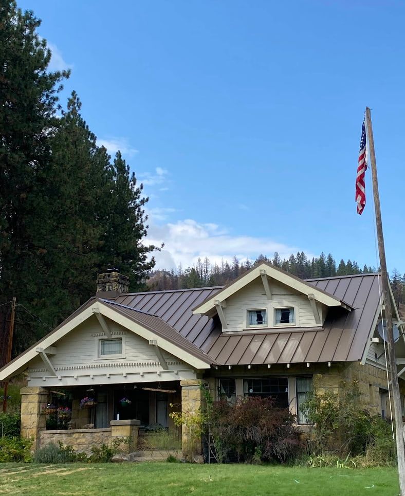 Stone cottage with a metal roof and an American flag.