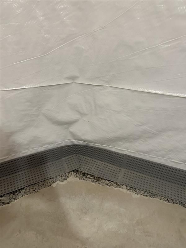 White and gray tarp corner, showing seams and a perforated edge.