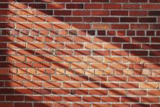 Brick wall with diagonal shadow stripes.