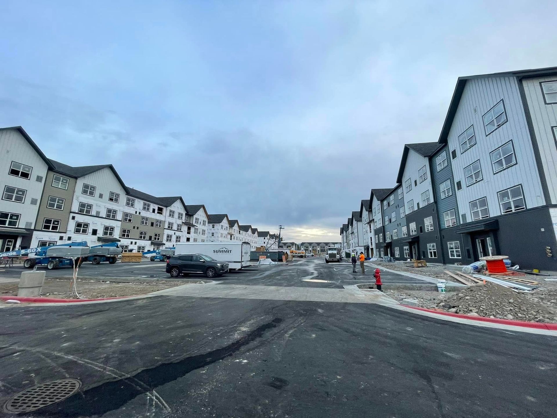 Construction site with rows of multi-story apartment buildings under a cloudy sky.