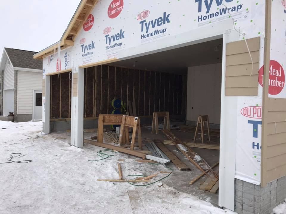 Garage under construction, exterior view. Framing, Tyvek wrap, snow on ground.