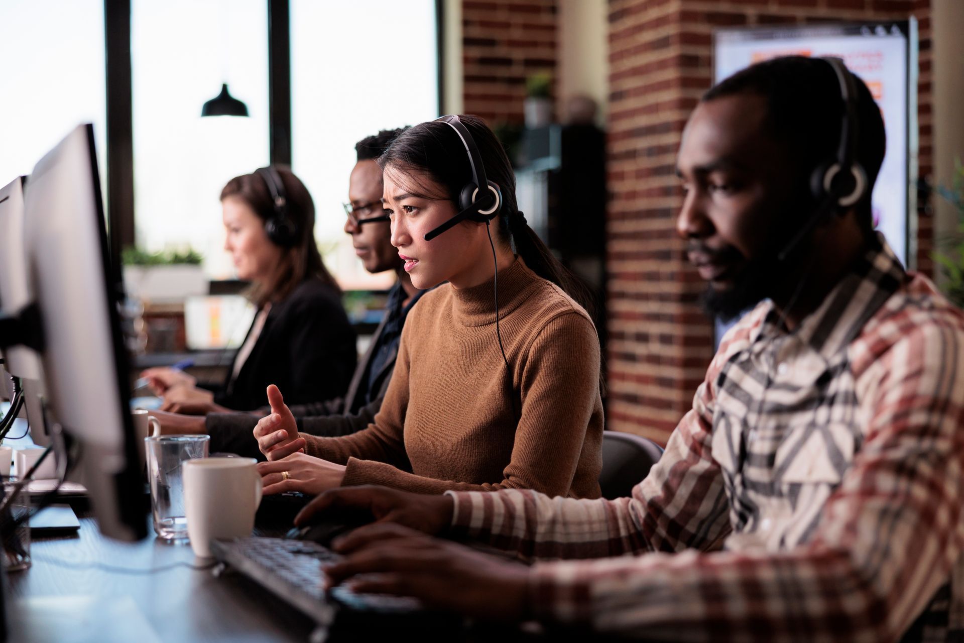 A group of people wearing headsets are working on computers in a call center.
