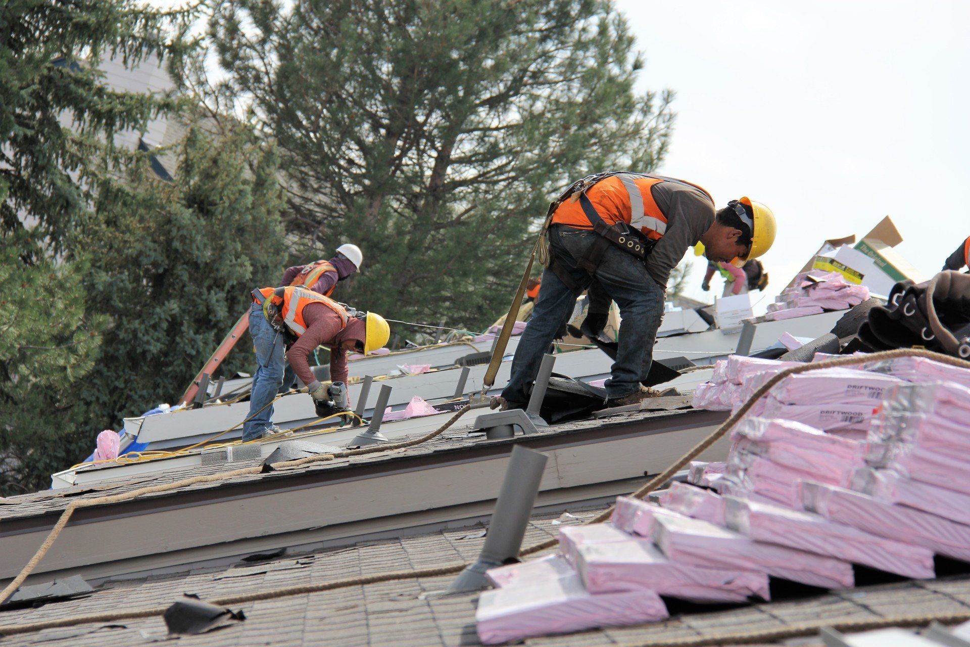 Three roofing workers can be seen working together for the installation of a new roof.