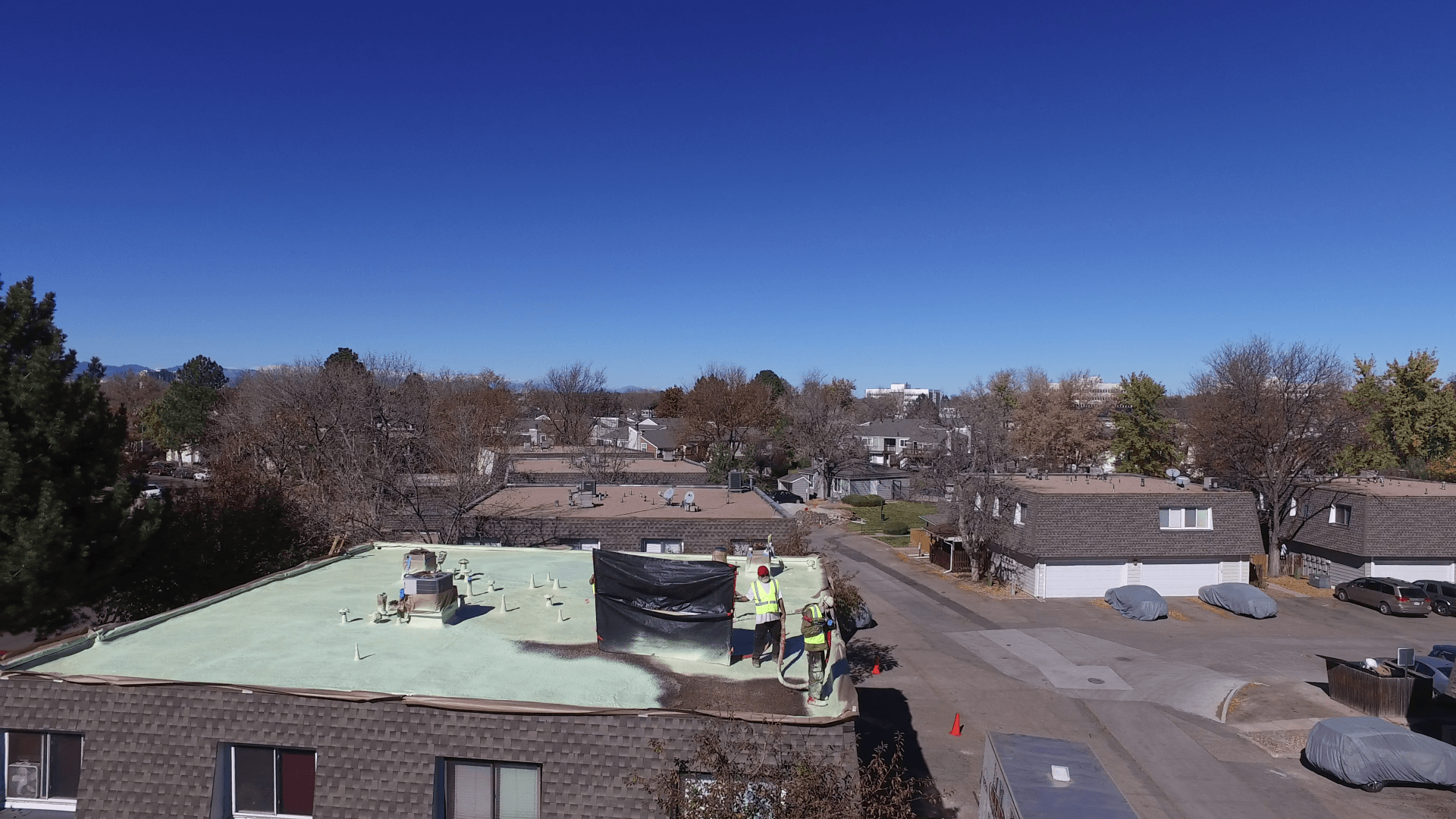 The roofing crew working as a team finishing up the coating of a roof.