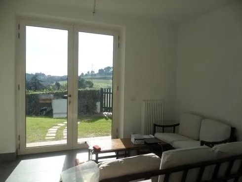 Luminoso soggiorno con doppie porte che si aprono sul cortile. 