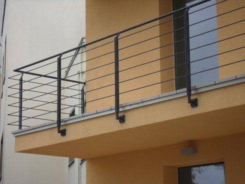 Ringhiera in metallo nero per balcone su un edificio color cuoio.