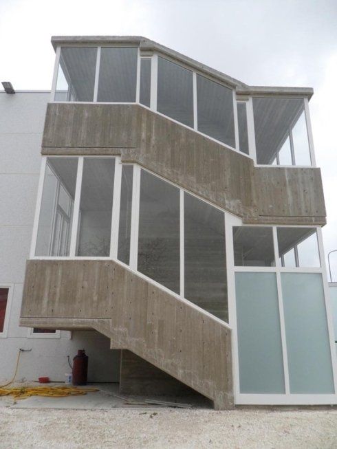 Scala esterna in cemento con finestre in vetro a cornici bianche.