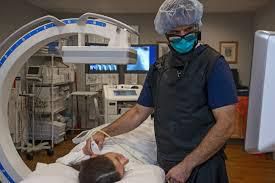 A surgeon is standing next to a patient in a hospital bed.