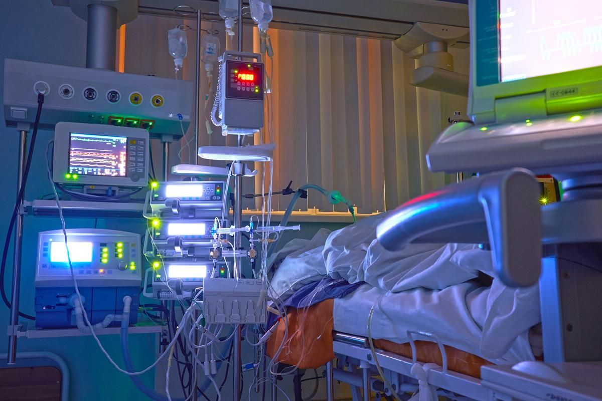 A hospital room with a bed and a lot of medical equipment.