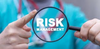 A person is holding a magnifying glass with the word risk management on it.
