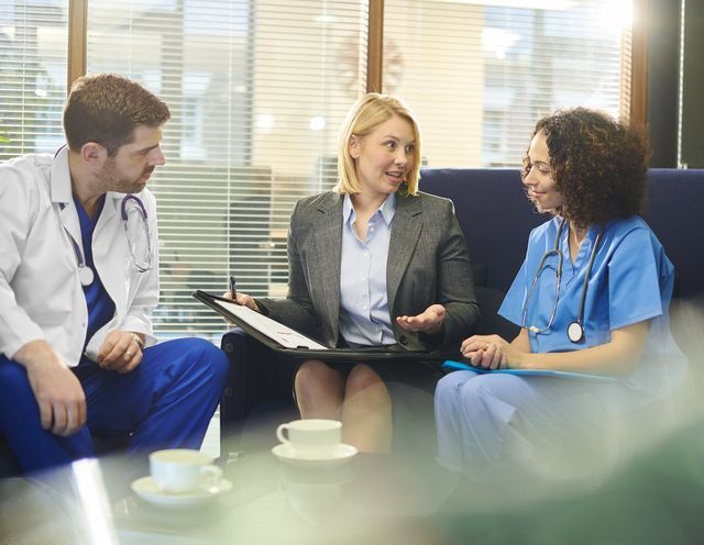 a group of doctors and nurses are sitting on a couch having a conversation